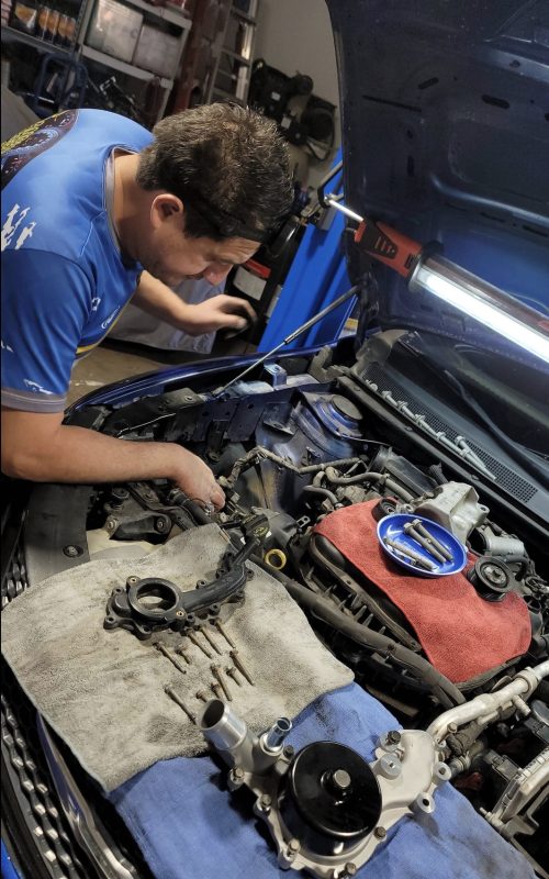 Mecánico realizando una inspección detallada del motor en Sánchez Auto Repair, taller en Glendale, Arizona.